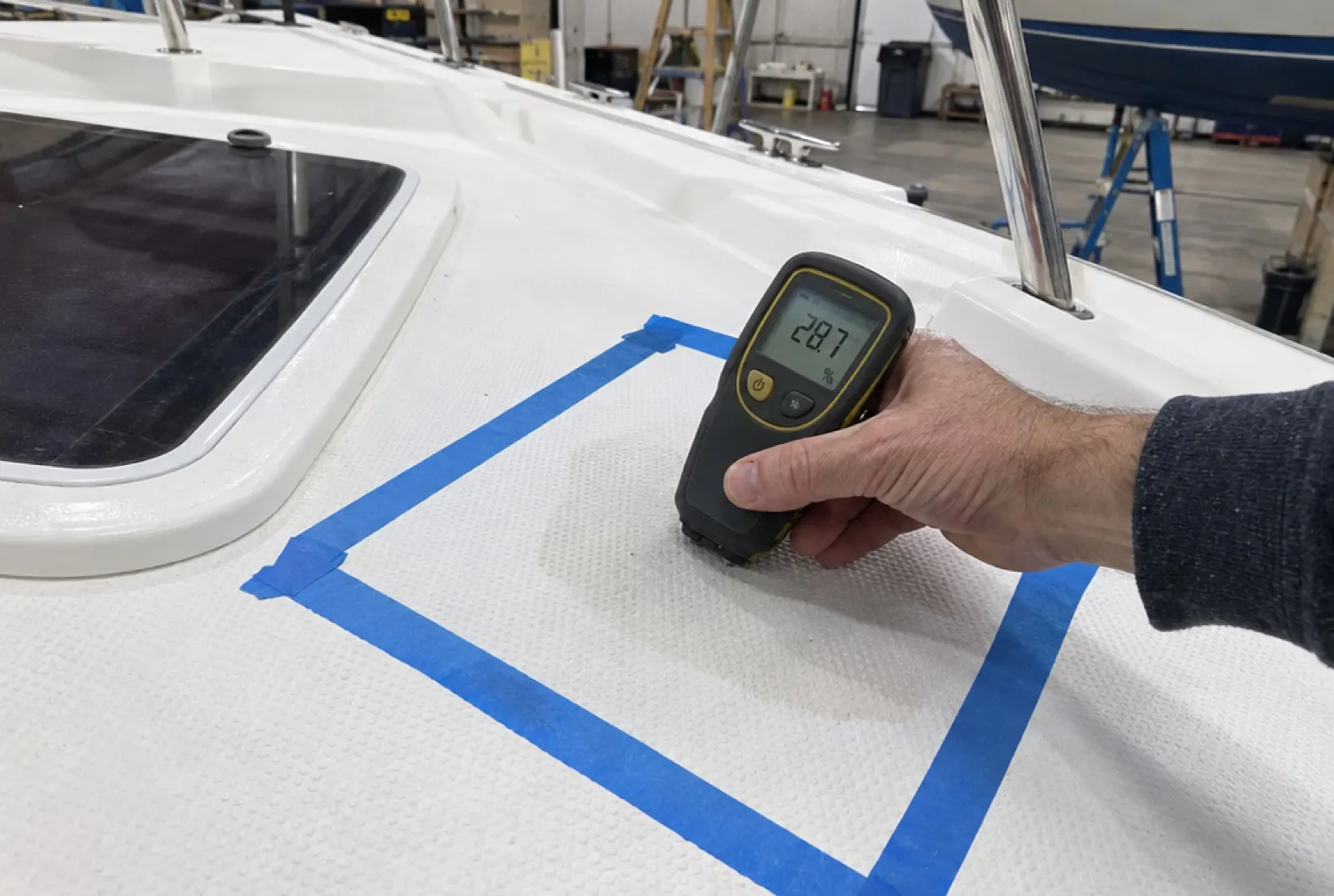 A moisture meter showing a high reading on a taped-off soft deck section