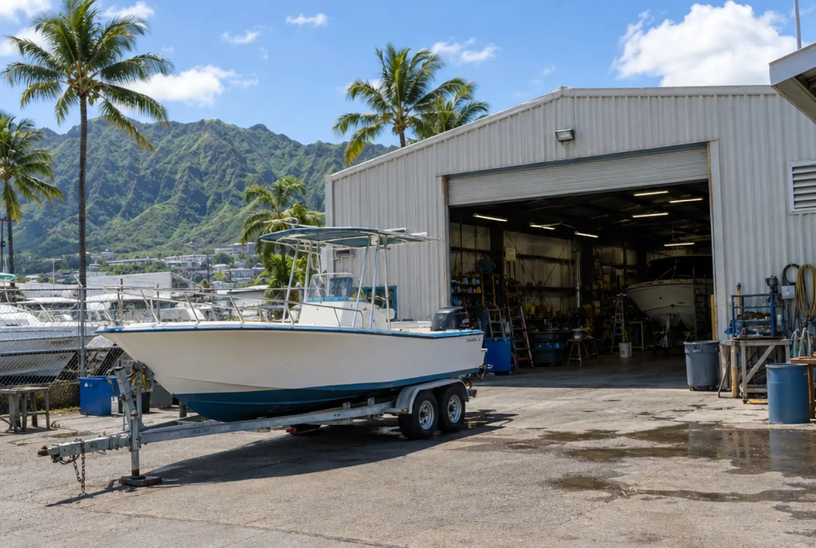 A metal shop building with its roll-up door open and a boat on a trailer out front