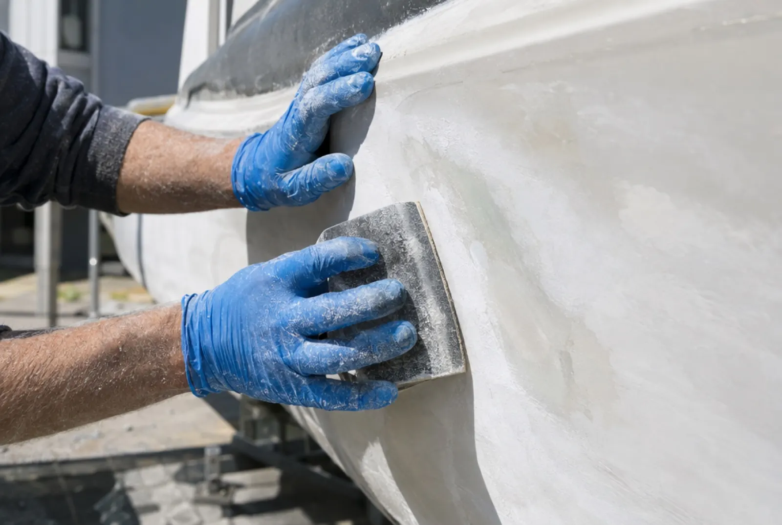Gloved hands sanding a faired fiberglass panel